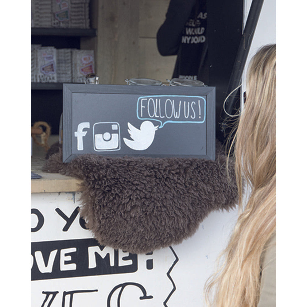 schwarze Kreidetafel mit Holzrahmen aufgestellt in einem Foodtruck, Follow us Beschriftung